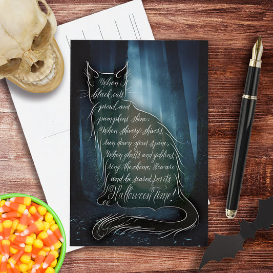 Lifestyle image of the Halloween black cat postcard: "When black cats prowl, and pumpkins shine..."