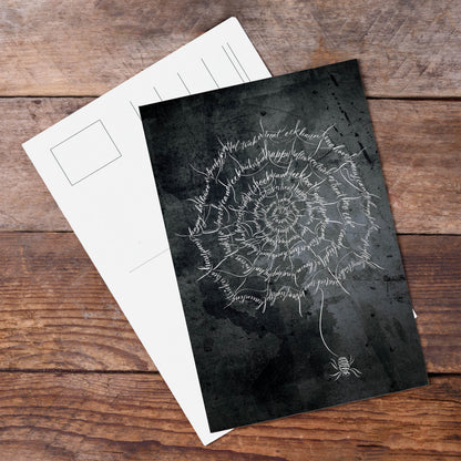 A top lifestyle view of the Halloween calligraphy postcard: "spider web" design