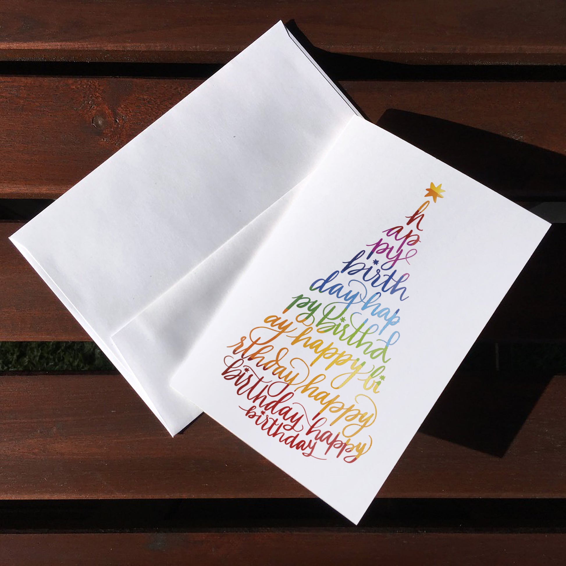 A top view of the greeting card: "Happy Birthday" written with calligraphy in the form of a party hat