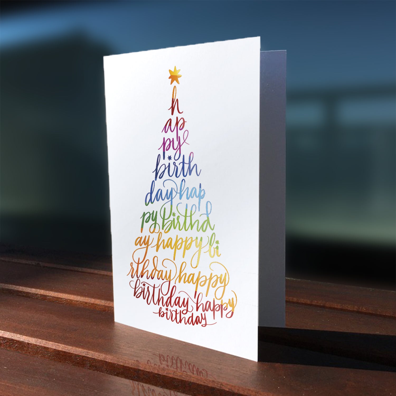 A lifestyle view of the greeting card: "Happy Birthday" written with modern calligraphy in the form of a party hat