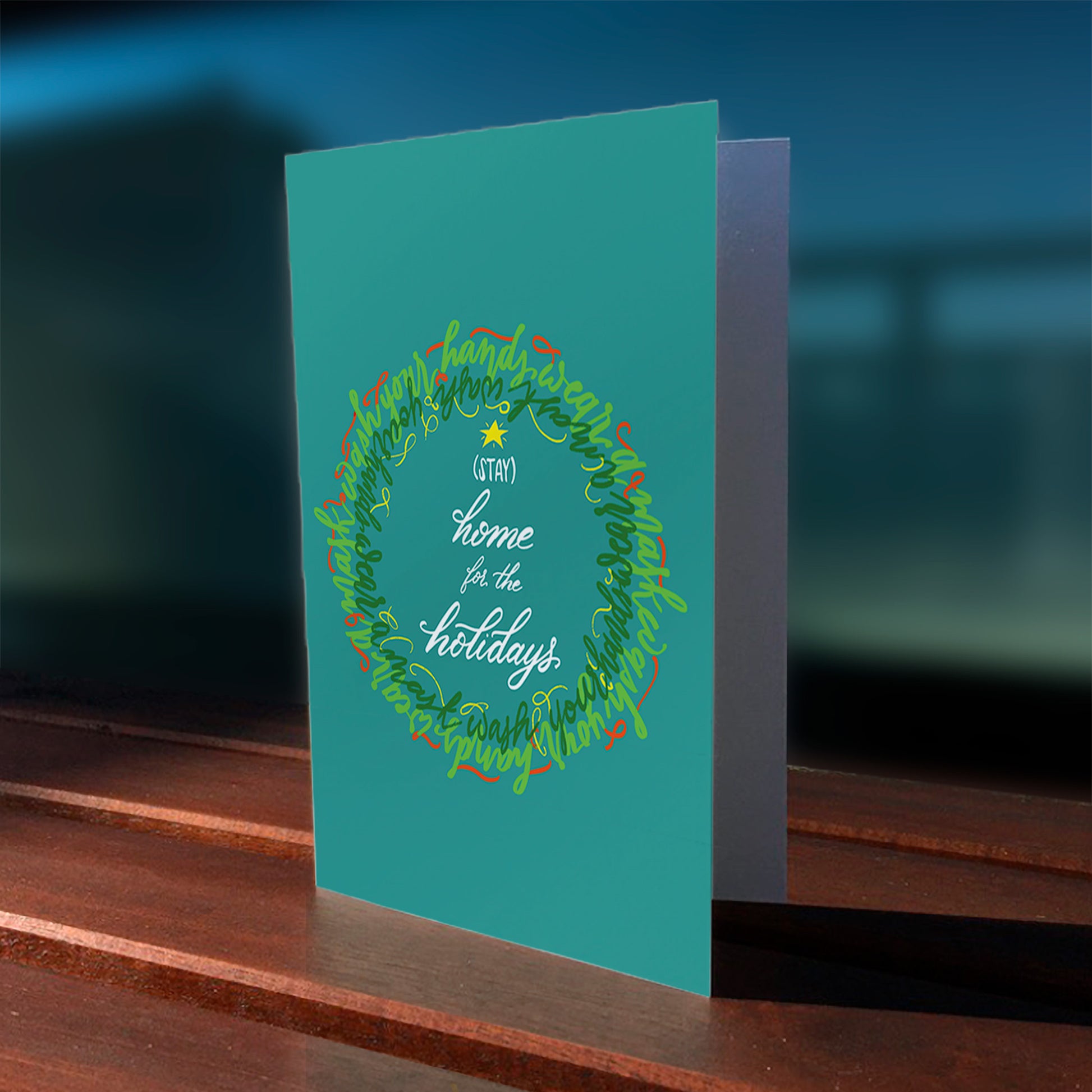 A lifestyle view of the greeting card: "Stay home for the holidays!"